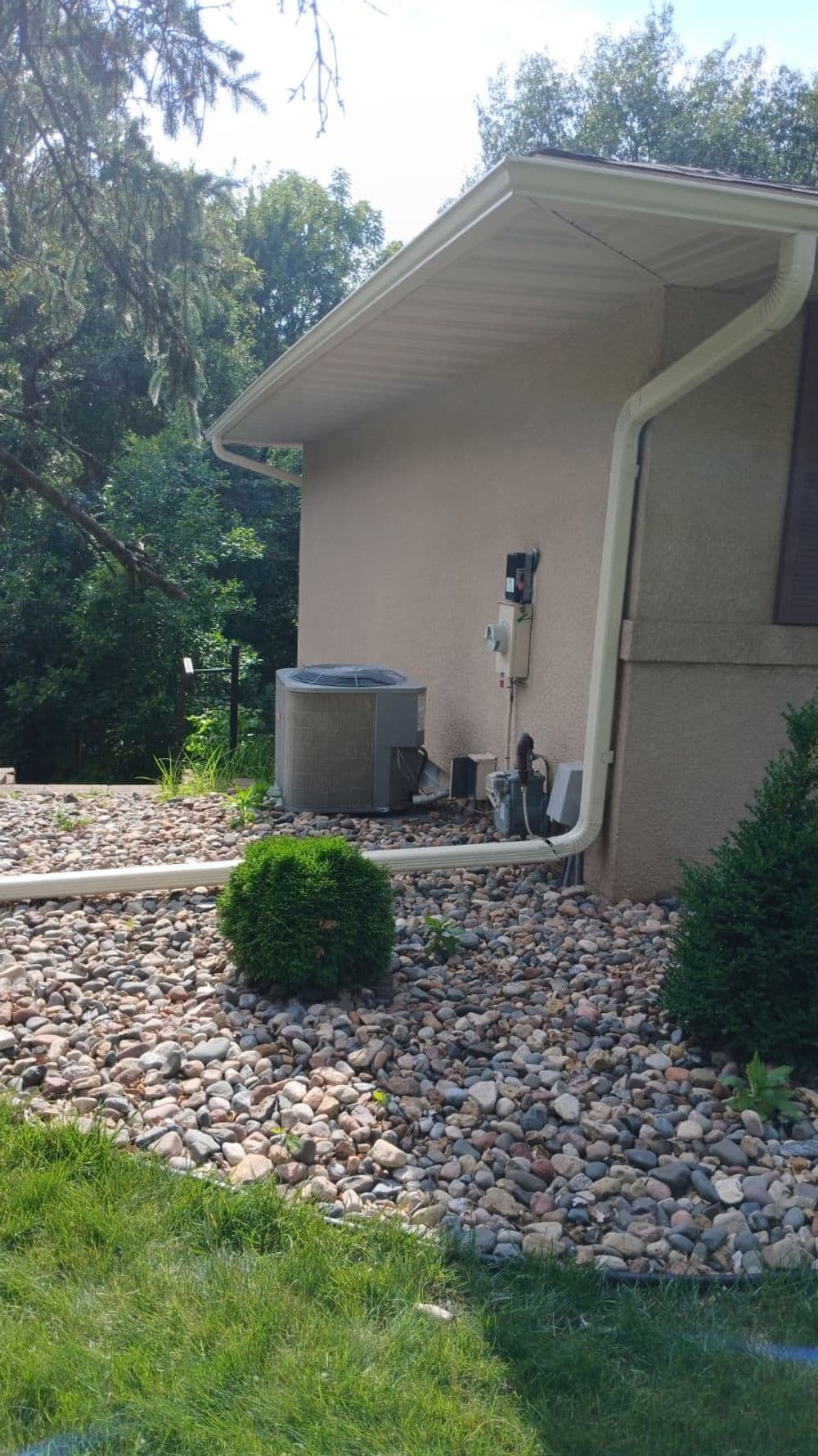 Air conditioning unit beside a house, surrounded by decorative rocks and landscaping.