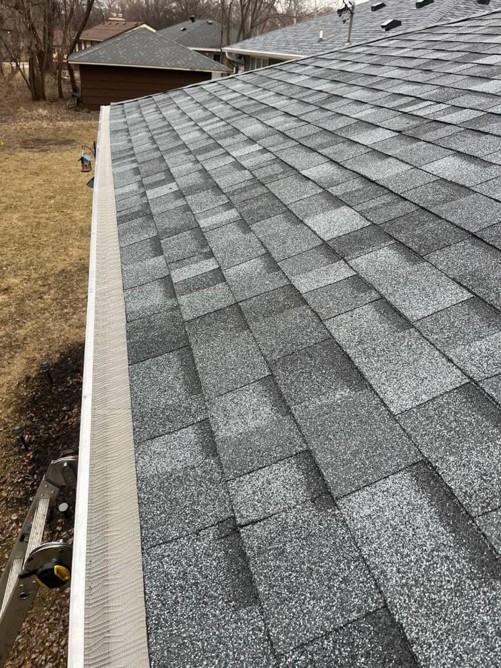 View of a gray shingle roof with gutters, showcasing residential roofing details.