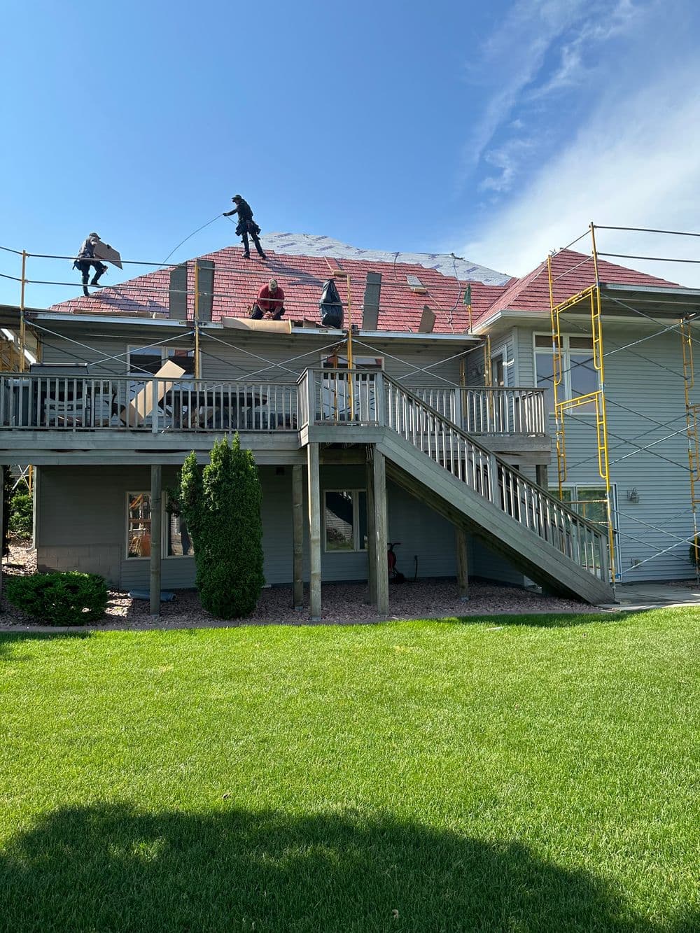 Roofers working on a residential home renovation project with scaffolding and tools visible.